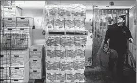  ??  ?? An employee checks a stack of off-brand paper goods in storage at Potash Market.