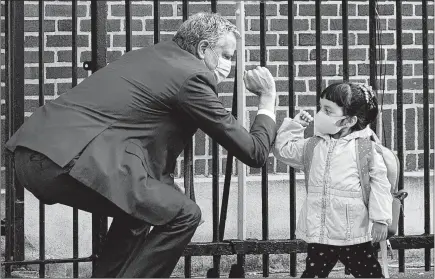  ?? TODD HEISLER/THE NEW YORK TIMES ?? Mayor Bill de Blasio greets a student this week at Mosaic Pre-K Center in the Queens borough of New York City by bumping elbows.