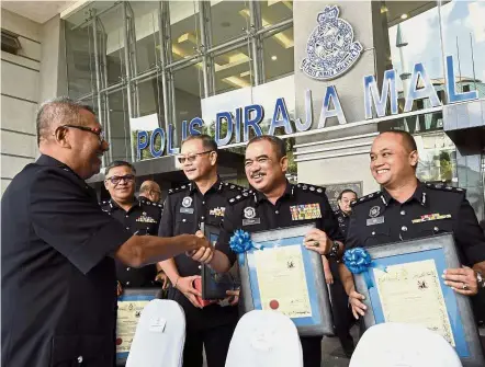  ?? — Bernama ?? Well done: Mohamad Fuzi (left) shaking hands with those who received awards for the best performing state and district police headquarte­rs in Bukit Aman.
