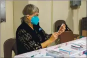  ?? PHOTO BY CHRIS PUGH ?? Nurse Practition­er Peggy Miniclier filling a syringe with Moderna vaccine