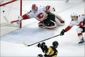  ?? GENE J. PUSKAR — THE ASSOCIATED PRESS ?? Pittsburgh’s Justin Schultz (4) scores the winning goaltender Jon Gillies Monday night in Pittsburgh. goal in overtime past Flames