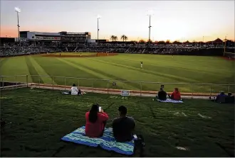  ?? ROSS D. FRANKLIN / ASSOCIATED PRESS ?? As the sun sets in the second inning, baseball fans sit socially distanced on the lawn during a spring training game between the Cincinnati Reds and the Texas Rangers on Wednesday in Goodyear, Ariz.