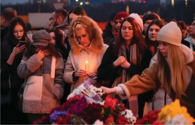  ?? Foto: Aleksander Zemlianits­jenko,, AP/NTB ?? U Folk strømmer til med blomster og lys til et minnested i nærheten av konserthal­len som ble angrepet fredag kveld.
