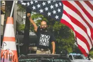  ??  ?? George Floyd’s name is written on the windshield as John Coy wears a shirt that reads Black Lives Matter and stands through his sunroof with his fist in the air at 16th Street Northwest renamed Black Lives Matter Plaza near the White House in Washington.
(AP/Andrew Harnik)