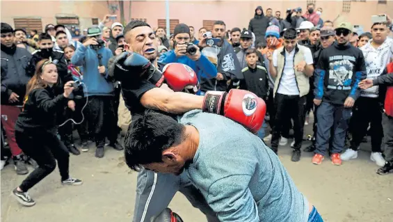  ?? EMMANUEL FERNÁNDEZ ?? Al frente. Dos jóvenes combaten en el barrio “Juan el Bueno”, de Berazategu­i, rodeados de un centenar de vecinos.