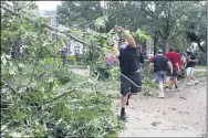  ?? LIZ MARTIN — THE GAZETTE VIA AP ?? Coe College left tackle Joshua Robles clears trees with other members of the Coe College football team from campus sidewalks Aug. 10in Cedar Rapids after a powerful storm with straight-line winds moved through Iowa.