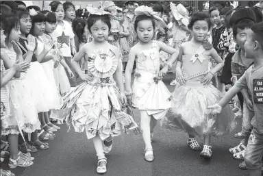  ?? WANG BIAO / FOR CHINA DAILY ?? Children wearing recycled paper walk through the audience at a kindergart­en fashion show promoting environmen­tal awareness in Fuyang, Anhui province, on Tuesday.