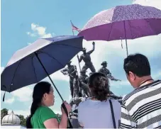  ??  ?? Sun shade: Tourists using umbrellas while at the National Monument, in Kuala Lumpur during the current hot spell.