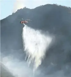  ?? HANDOUT/THE ASSOCIATED PRESS ?? In this photo provided by the Santa Barbara County Fire Department, a Sikorsky S-64 Skycrane makes a water drop on hot spots along the hillside east of Gibraltar Road in Santa Barbara, Calif., Sunday morning. One of the largest wildfires in California...