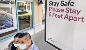  ?? Chris O'meara / Associated Press ?? Shoppers wear protective face masks as they walk past a social distancing sign in Ellenton, Fla. Social distancing mandates have hindered the medical exams required for life insurance applicatio­ns.