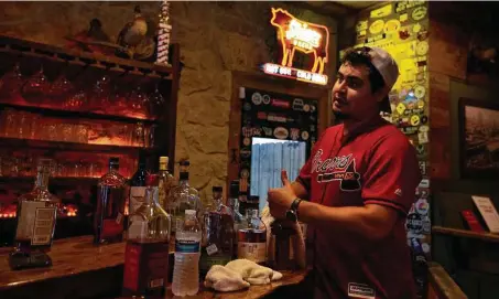  ?? Yi-Chin Lee / Staff photograph­er ?? Pinkerton’s Barbecue bartender Xavier Jones cleans liquor bottles Tuesday before putting them back on the shelves.