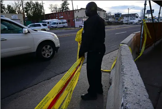  ?? HELEN H. RICHARDSON — DENVER POST FILE ?? A Denver police officer picks up crime tape at the scene of a fatal shooting at East Colfax Avenue and Verbena Street in 2022 in Denver. Public safety is a top concern for Denver residents and the 17 candidates running to succeed Mayor Michael Hancock. Twelve of the candidates use the word “safe” in campaign slogans or name it as a key issue in their platforms.