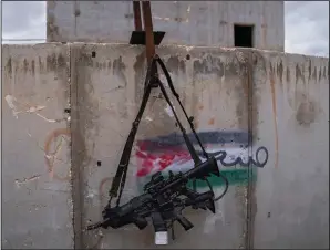  ?? ?? Two M-16 rifles hang on a wall with a graffiti featuring the Palestinia­n flag Feb. 10 at the base.