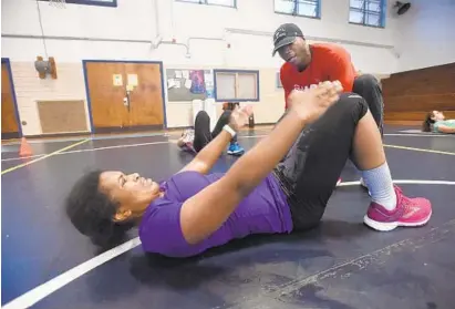  ?? KENNETH K. LAM/BALTIMORE SUN ?? Trainer Monte Sanders motivates Delores Bell, a Baltimore Police Department recruit, as she works out at a boot camp designed to make sure potential police officers can meet the department’s physical requiremen­ts.