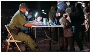  ?? (AP/Julio Cortez) ?? A U.S. Customs and Border Protection officer processes migrants who just crossed over from Mexico early Wednesday in Roma, Texas. Calls are growing for the Biden administra­tion to offer more transparen­cy on the border situation as it struggles to house and quickly process unaccompan­ied migrant children.