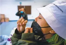  ?? NELVIN C. CEPEDA U-T ?? Kaira Fenix gathers a sample for a coronaviru­s test at a county-run testing site in City Heights in December.