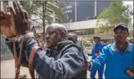  ?? ?? Pasha (left) is arrested Friday by a police officer after police used tear gas to break up a small demonstrat­ion of Maasai rights activists outside the Tanzanian high commission in downtown Nairobi.