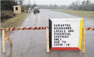  ?? CLIFFORD SKARSTEDT EXAMINER ?? A resident picks up mail Thursday at the Kawartha Nishnawbe First Nation checkpoint at Ojibway Road South near Burleigh Falls that has been set up to help stop the spread of the COVID-19 virus.