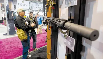  ?? (Steve Marcus/Las Vegas Sun/Reuters) ?? ATTENDEES EXAMINE Remington rifles and shotguns during the annual SHOT (Shooting, Hunting, Outdoor Trade) Show in Las Vegas in 2013.