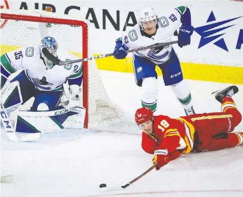  ?? — THE CANADIAN PRESS ?? Canucks centre Jay Beagle knocks Calgary Flames forward Matthew Tkachuk off his feet behind goaltender Thatcher Demko's net Monday on a night Vancouver took too many penalties.