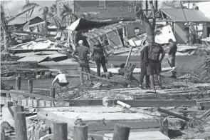  ?? GERALD HERBERT/AP ?? People stand on the destroyed bridge to Pine Island as they view the damage in the aftermath of Hurricane Ian in Matlacha, Florida, on Sunday. A temporary passageway to the island will be built.