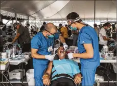  ?? MIKE BELLEME / THE NEW YORK ?? Senior dental students work on a patient in Wise, Va. Obamacare enrollment through the federal website Healthcare. gov is down 11 percent compared to 2017, government figures say.