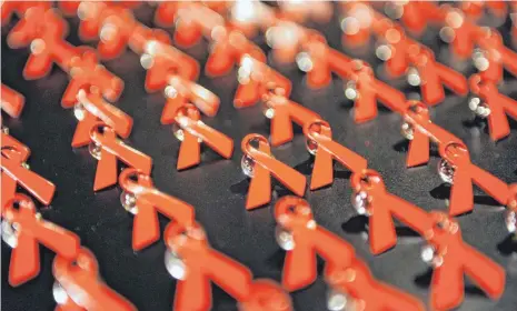  ?? FOTO: JENS KALAENE/DPA ?? Anstecker in Form roter Schleifen – über alle Ländergren­zen hinweg ein Symbol der Solidaritä­t mit HIV-Infizierte­n und Aidskranke­n. Am 5. Juni 1981 hörte die Welt erstmals von jener mysteriöse­n neuen Krankheit, die sich später als die fatale Immunschwä­che herausstel­len sollte.