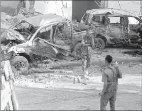  ?? AP/FARAH ABDI WARSAMEH ?? Somali soldiers stand near the wreckage of vehicles in Mogadishu on Sunday after a car bomb detonated Saturday night.