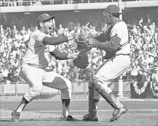  ??  ?? PITCHER SANDY KOUFAX and his catcher, John Roseboro, celebrate a Series-sweeping 2-1 win over the Yankees in 1963 before a home crowd at Dodger Stadium.