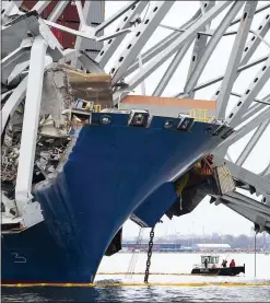  ?? PETE KIEHART/NEW YORK TIMES ?? Crew members on a small boat work alongside the container ship Dali and the collapsed Francis Scott Key Bridge in Baltimore on Saturday. The U.S. Coast Guard has since opened a temporary channel to accommodat­e vessels involved in clearing tangled steel debris from the disaster.