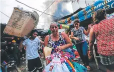  ?? FOTO: AFP ?? Las personas corrían para rescatar mercadería mientras el fuego avanzaba, unos 25 puestos quedaron reducidos a cenizas.