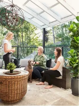  ??  ?? OUTDOOR TERRACE The green outlook inspired Audrey (pictured, above left, with Erin, left, Annika and Finn the weimaraner) to turn the terrace into an outdoor room, adding an L-shaped outdoor lounge
(try Bunnings) and a ‘Foucault’ pendant light from Canalside Interiors. Finn often pads through the colonial-style doors from Airlite (above right).