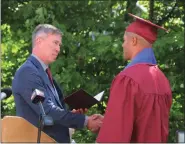  ?? ?? Fitchburg Public Schools Superinten­dent Robert Jokela, left, presents Goodrich Academy senior Mathews Cardeal with his high school diploma during a special graduation ceremony held for the 21-year-old on Monday.