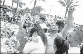 ?? DAVID GOLDMAN/ASSOCIATED PRESS ?? Jose Hernandez (center) joins hands with Victor Baez (right) as they mourn the loss of their friends Amanda Alvear and Mercedez Flores at a makeshift memorial for the shooting victims.