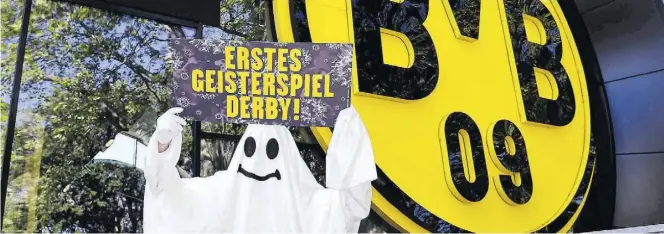  ?? BILD: IMAGO ?? Vor dem Bundesliga-Neustart: Ein verkleidet­er Fan steht vor dem Signal Iduna Park und zeigt vor dem Derby Dortmund - Schalke ein Transparen­t.