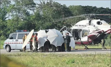  ?? Lillian Suwanrumph­a AFP/Getty Images ?? THAI police and military personnel surround a stretcher at a military airport in Chiang Rai. The boys rescued from a f looded cave were taken to a hospital by ambulance and helicopter, according to authoritie­s.