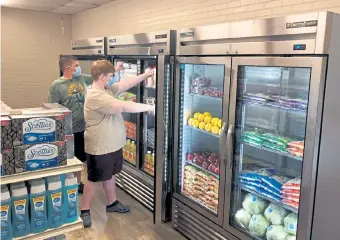  ?? Courtesy of Anthony Love ?? Hunter Weertman, 16, left, works alongside a fellow student to stock the refrigerat­ors in the studentled free grocery store at Linda Tutt High School on Nov. 20 in Sanger, Texas. “I like seeing their smiles, seeing how appreciati­ve they are, and knowing that they are thankful that we’re doing something like this,” Weertman said.