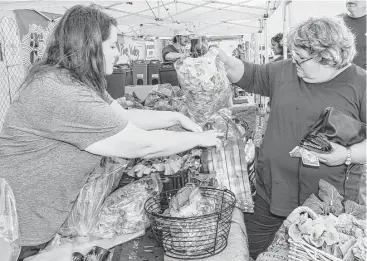  ?? Kim Christense­n photos / For the Chronicle ?? Heidi Hall with Island Aquaponics sells some of her vegetables to Cathy McLean of Galveston at the Galveston Farmers Market, which opened in 2012.