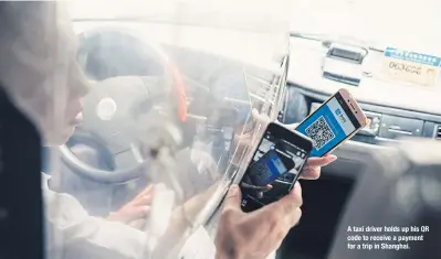  ??  ?? A taxi driver holds up his QR code to receive a payment for a trip in Shanghai.