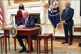  ?? DOUG MILLS / THE NEW YORK TIMES ?? President Joe Biden signs executive orders Thursday that outline his administra­tion’s response to the COVID-19 pandemic.