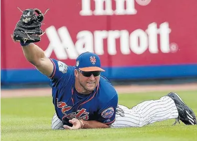  ?? JOHN BAZEMORE/AP ?? Mets left fielder Tim Tebow makes a diving catch on a fly ball by Miami Marlins’ Justin Bour in the second inning of Monday’s spring training baseball game in Port St. Lucie. He also had his first hit of the spring in the game.