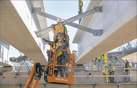  ?? Antonella Crescimben­i/Post-Gazette ?? Constructi­on workers attach X-shaped steel braces between precast concrete beams placed for constructi­on of a bridge over Little Raccoon Creek in Robinson, Washington County, as part of the $800 million Southern Beltway.