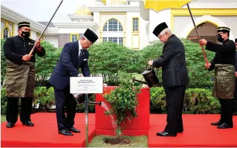  ?? Bernama photo — ?? Al-Sultan Abdullah (left) and Tuanku Muhriz jointly water the tree after the planting ceremony at Istana Negara.