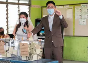  ?? ?? Dressed for another occasion: Cheng and Choo casting their votes at Sekolah Kebangsaan Taman Sri muda, Shah alam before rushing to the church wedding. — yap Chee Hong/the Star