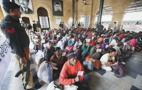  ?? AP ?? A police officer guards Indian fishermen waiting at a railway station to leave for their home country, in Karachi, yesterday. Pakistan released 147 Indian fishermen, who had been held for illegally fishing in Pakistani waters.
