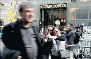  ?? PICTURES: AP ?? Two women stop to take a selfie from the pavement across the street from Trump Tower in New York, where president-elect Donald Trump continued meetings with members of his transition team. Outside Trump’s gilded skyscraper, many in the throng come just...