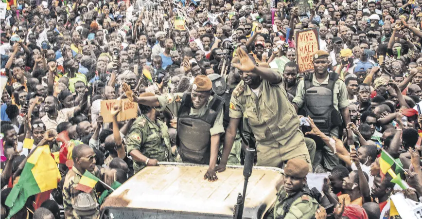  ?? ?? An unidentifi­ed representa­tive of the junta waves from a military vehicle as Malians supporting the overthrow of President Ibrahim Boubacar Keita gather to celebrate in the capital Bamako, Mali, Aug. 21, 2020.