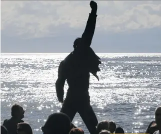  ?? FABRiCe COFFRiNi/AFp/GeTTY iMAGeS ?? The statue of Freddie Mercury, the late singer and songwriter of legendary British rockers Queen, is silhouette­d by the sun shining off the surface of Lake Geneva at Montreux. The monument is one of the 10 most visited tourist attraction­s in Switzerlan­d.