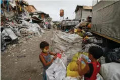  ?? ( Eloisa Lopez/ Reuters) ?? BOYS WEAR masks to protect against COVID- 19 as they remove labels from plastic bottles in Tondo, Manila, Philippine­s, in July.