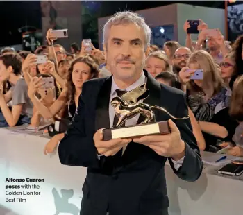  ??  ?? Alfonso Cuaron poses with the Golden Lion for Best Film